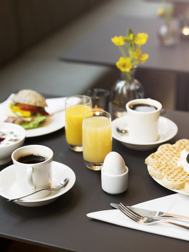 Frukost uppdukad på bord med juice, kaffe och våfflor
