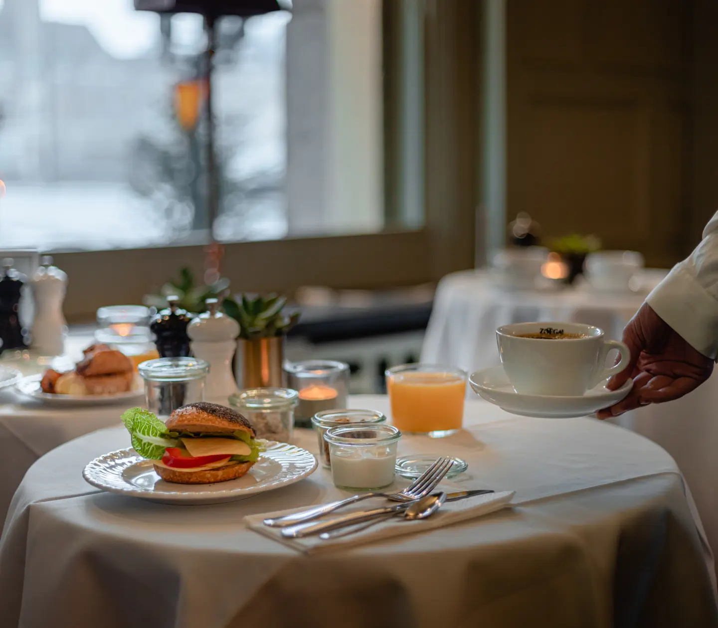 A waiter serves a cup of coffee to the breakfast table