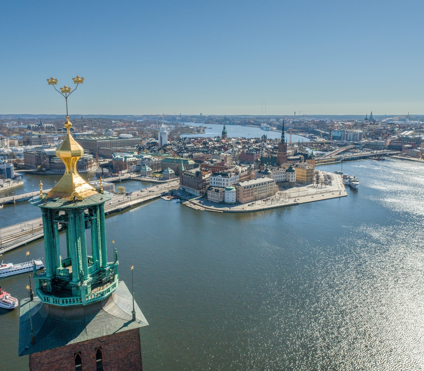 Aerial view of Stockholm skyline with City Hall tower foreground and glittering waterways.
