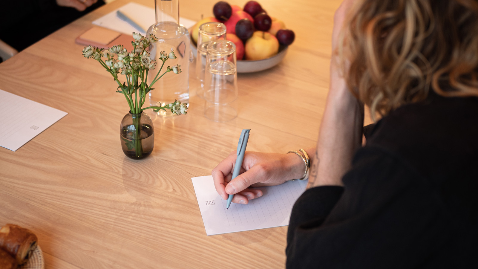 Kvinna skriver på ett papper sittandes vid ett konferensbord